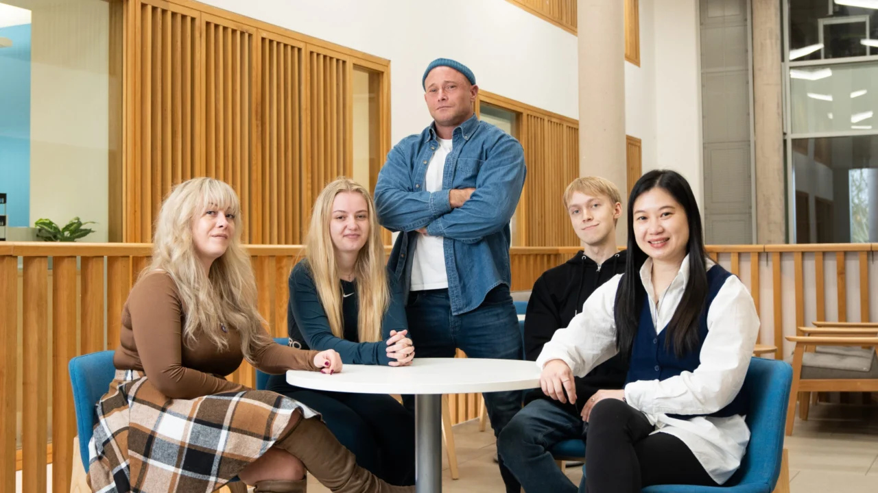 Five students standing and seated around a table
