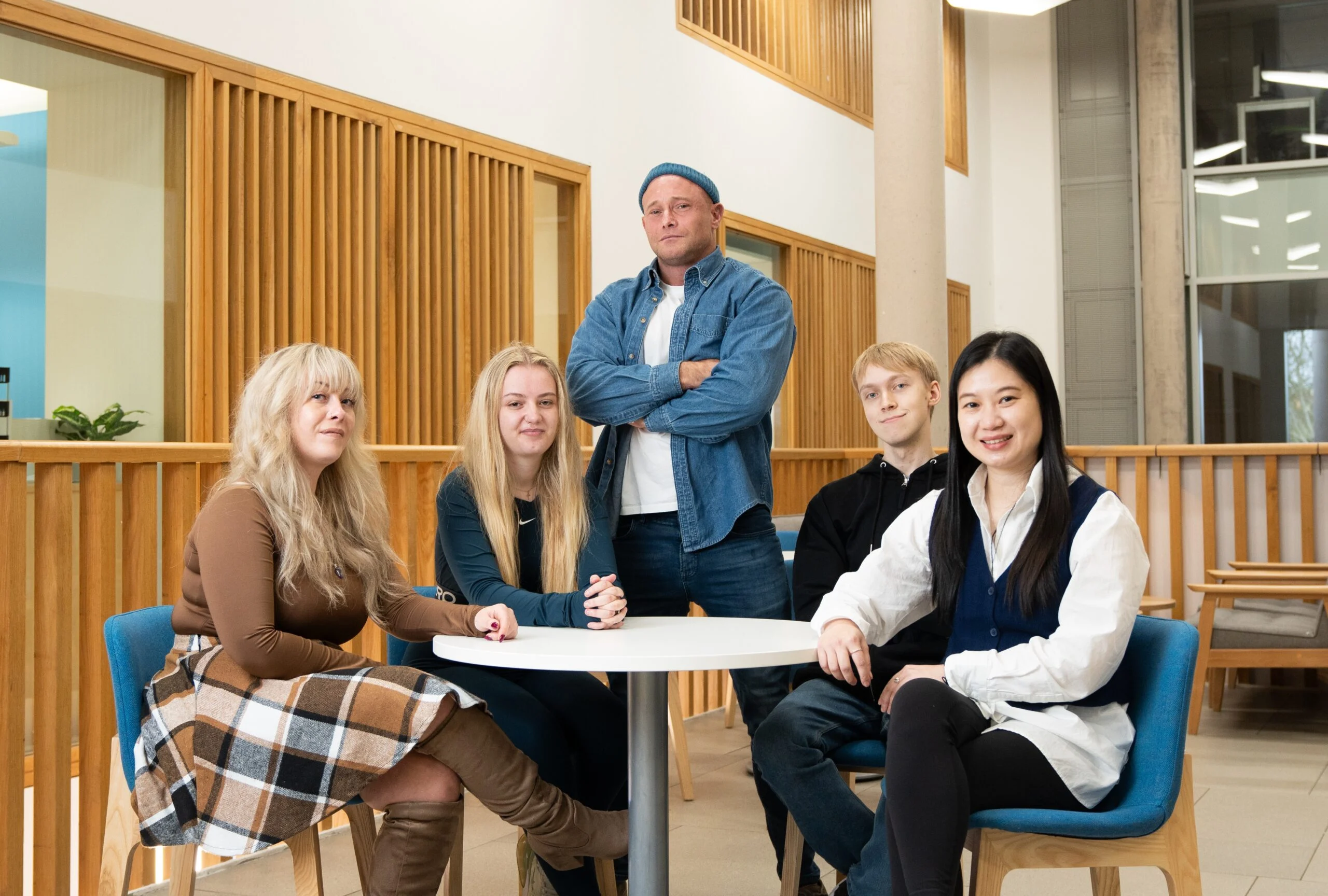 Five students standing and seated around a table