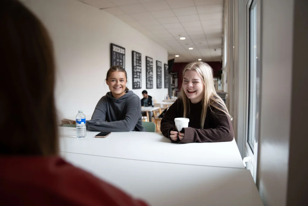 Students sitting and chatting in Bistro32 at Victoria University, with a bright, modern interior and casual dining atmosphere.