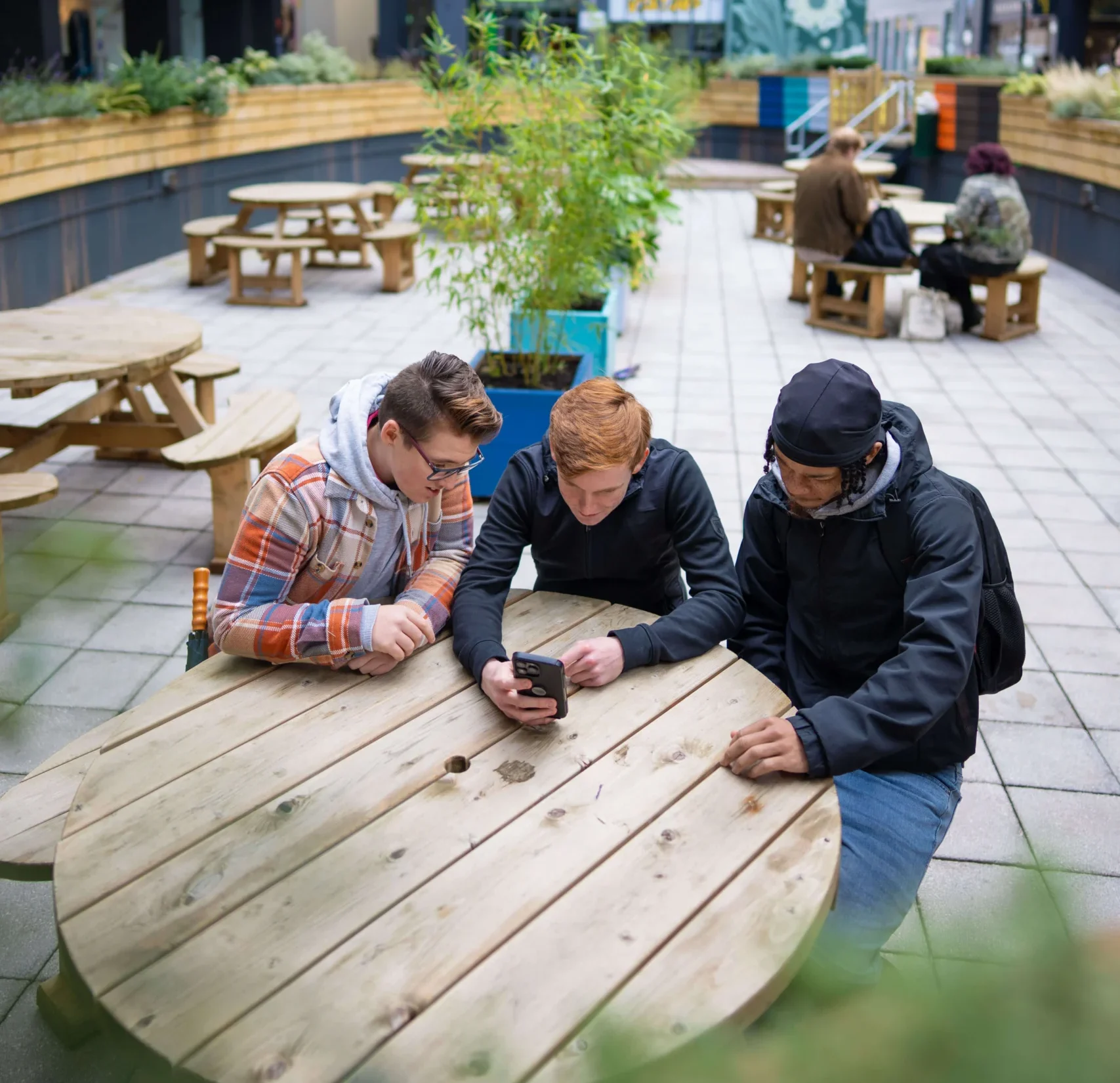 Students sitting at a table looking at mobile phone